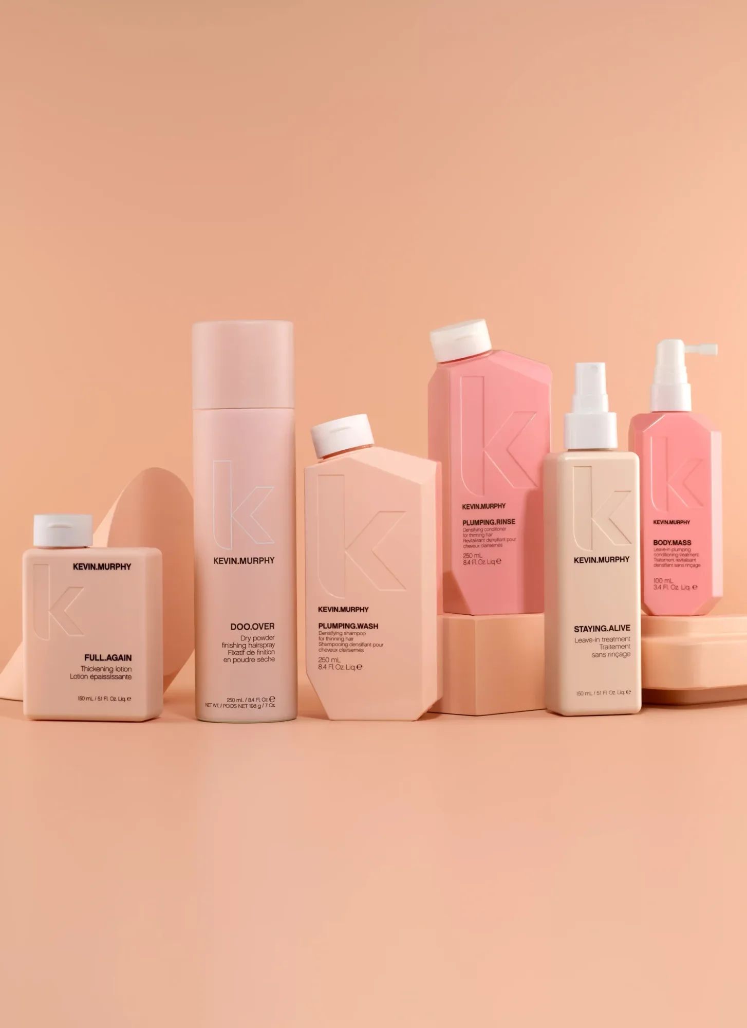 Een rij verzorgingsproducten van Kevin Murphy tegen een roze achtergrond